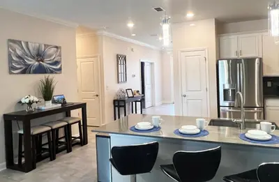 a kitchen and living room with a table and chairs at Luxury Lake View 9-Bedroom Villa @Storey Lake Resort in Kissimmee
