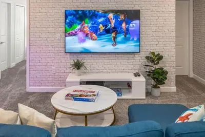 a living room with a tv on a brick wall at Luxury Lake View 9-Bedroom Villa @Storey Lake Resort in Kissimmee