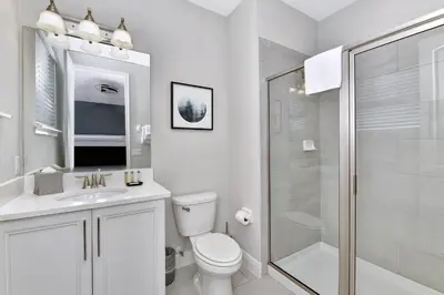 a white bathroom with a toilet and a shower at Modern Home With Themed Rooms, Foosball Table And Waterpark & Resort Access Near Disney At Encore Resorts Reunion - 253Sf in Kissimmee