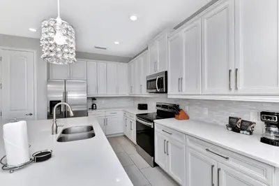 a white kitchen with white cabinets and a sink at Modern Home With Themed Rooms, Foosball Table And Waterpark & Resort Access Near Disney At Encore Resorts Reunion - 253Sf in Kissimmee