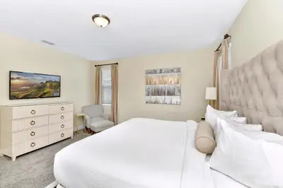 a white bedroom with a white bed and a chair at Glorious Home Near Disney With Private Pool, Game Room And Waterpark & Resort Access At Encore Resorts Reunion - 660La in Kissimmee