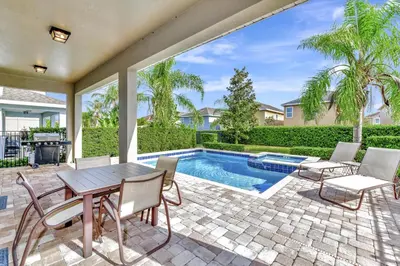 a patio with a table and chairs and a swimming pool at Glorious Home Near Disney With Private Pool, Game Room And Waterpark & Resort Access At Encore Resorts Reunion - 660La in Kissimmee