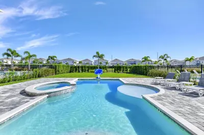 a swimming pool with a patio and chairs in a yard at Stylish Home With Themed Rooms, Game Room And Waterpark & Resort Access Near Disney At Encore Resorts Reunion - 267Sf in Kissimmee