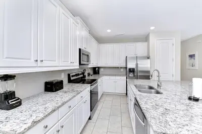 a white kitchen with white cabinets and a sink at Stylish Home With Themed Rooms, Game Room And Waterpark & Resort Access Near Disney At Encore Resorts Reunion - 267Sf in Kissimmee
