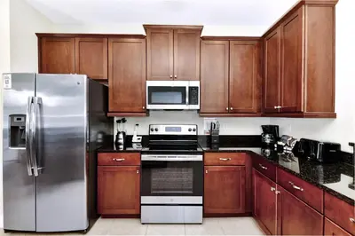 a kitchen with wooden cabinets and stainless steel appliances at Gorgeous Home With Private Pool, Game Room Near Disney With Waterpark & Resort Access At Encore Resort - 781La in Kissimmee