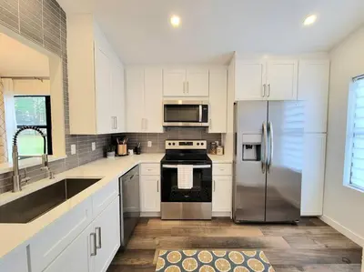 a kitchen with white cabinets and a stainless steel refrigerator at Elegant Cozy Spot to unwind! UCF/MCO/Parks/Beach in Orlando