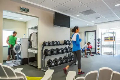 a woman walking through a gym with a tv at Home2 Suites By Hilton Winter Garden in Orlando