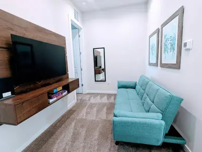 a living room with a blue couch and a flat screen tv at Cozy 2024 New 3 Suites 5 min to Disney in Orlando
