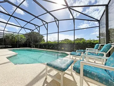 a swimming pool with chairs and a glassconservatory at Sunnyside Villa home in Kissimmee