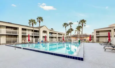 a swimming pool at a resort with chairs and umbrellas at Pool - WiFi - Parking - Best Location ! in Kissimmee
