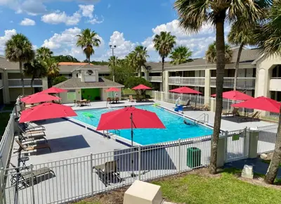 a pool with red umbrellas in a resort at Pool - WiFi - Parking - Best Location ! in Kissimmee