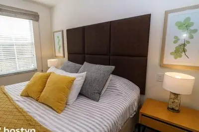 a bedroom with a large bed with yellow pillows at Beautiful Townhome w Hot Tub Near Disney in Kissimmee