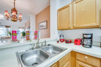 a kitchen with a sink and wooden cabinets at 4 Mi to Disney Emerald Island Resort Home! in Kissimmee