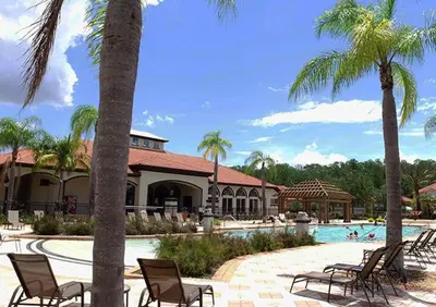 a resort with a pool with chairs and palm trees at Top Villas - Bella Vida Resort 203 in Kissimmee