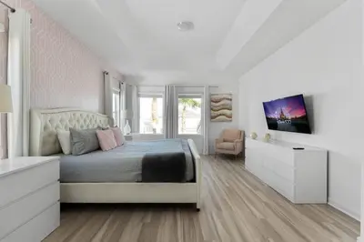 a white bedroom with a large bed and a chair at Last Minute Disney Private Pool Hot Tub Game Room Themed Bedrooms. Book Now 43123 in Kissimmee