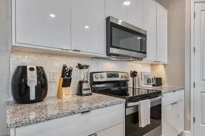 a kitchen with white cabinets and a stove top oven at Last Minute Disney Getaway Private Pool Themed Bedrooms. Book Now 81907 in Orlando