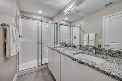a white bathroom with two sinks and a shower at Last Minute Disney Getaway! Private Pool, Hot Tub & Games Room. Book Now! #81903 in Orlando