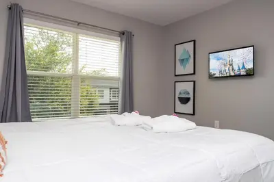 a large white bed in a bedroom with a window at Last Minute Disney Getaway Townhouse with Private Pool. Book Now 60511 in Kissimmee