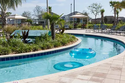 a blue swimming pool with chairs and tables in a resort at Last Minute Disney Getaway Private Pool Themed Bedrooms. Book Now 93749 in Kissimmee
