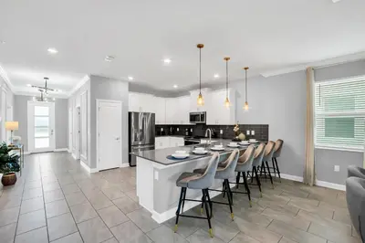 a kitchen and dining room with a large island with bar chairs at Storey Lake Resort 1095 - Hosted by Top Villas in Kissimmee