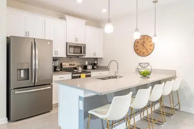 a kitchen with a stainless steel refrigerator and white cabinets at Storey Lake Resort 1113 - Hosted by Top Villas in Kissimmee