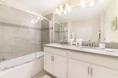a white bathroom with two sinks and a shower at Last Minute Disney Getaway Private Pool Themed Bedrooms. Book Now 98613 in Kissimmee
