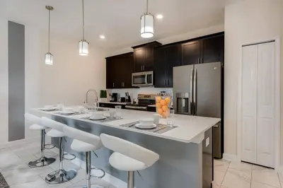 a kitchen with a counter with stools and a refrigerator at Last Minute Disney Getaway Private Pool Themed Bedrooms. Book Now 17254 in Kissimmee