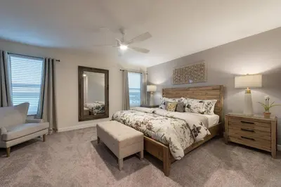 a bedroom with a bed and a chair and a mirror at Storey Lake Resort 61 - Hosted by Top Villas in Kissimmee