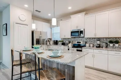 a kitchen with white cabinets and a island with chairs at Last Minute Disney Private Pool Hot Tub Themed Bedrooms. Book Now 17198 in Kissimmee
