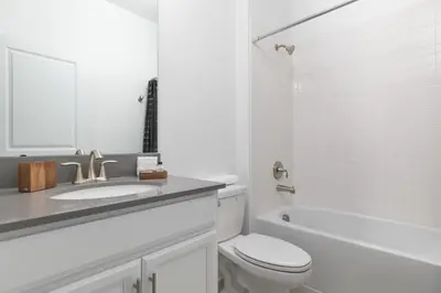 a white bathroom with a toilet and a sink at Last Minute Disney Private Pool Hot Tub Themed Bedrooms. Book Now 56873 in Kissimmee