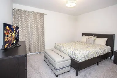 a bedroom with a bed and a tv and a chair at Last Minute Disney Getaway Villa with Private Pool Hot Tub. Book Now 22454 in Kissimmee