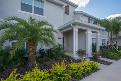 a white house with a palm tree in front of it at Last Minute Disney Getaway Townhouse with Private Pool. Book Now 17402 in Kissimmee