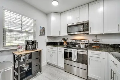 a kitchen with white cabinets and stainless steel appliances at Modern Florida Bungalow 3 Miles to Winter Garden! in Montverde