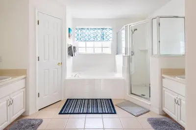 a white bathroom with a shower and a tub at Comfortable House with hot tub close to Disney in Kissimmee