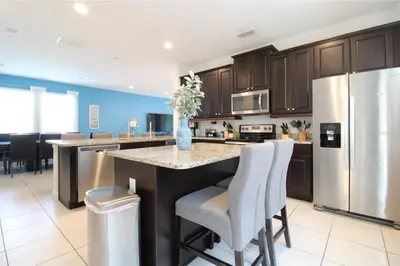 a kitchen with a island with chairs and a refrigerator at Family Themed House Close to Disney with Private Pool and Huge Backyard in Orlando