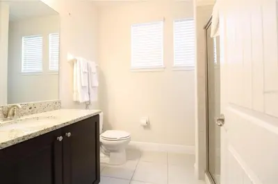 a white bathroom with a toilet and a sink at Family Themed House Close to Disney with Private Pool and Huge Backyard in Orlando