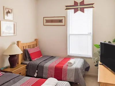a bedroom with two beds and a tv and a window at 4 Bed 2269 in Kissimmee