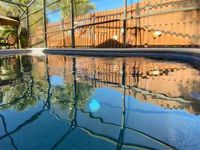 a swimming pool with a fence and its reflection in the water at 2 Bed 5325 in Kissimmee