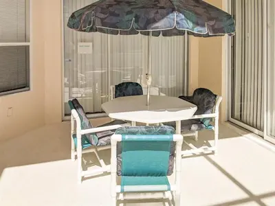 a table and chairs with an umbrella in a room at 5 Bed 8002 in Kissimmee