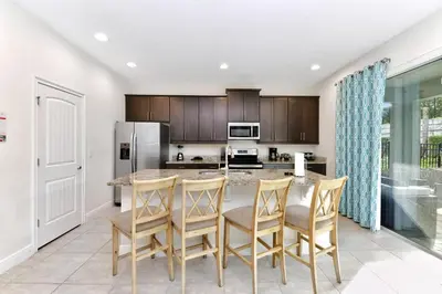 a kitchen with a large island with chairs around it at Charming Home With Themed Rooms, Game Room And Waterpark & Resort Access Near Disney At Encore Resorts Reunion - 300Pn in Kissimmee