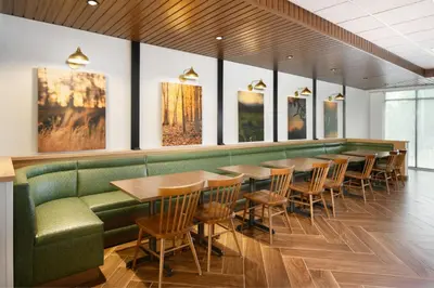 a dining room with tables and a green couch at Fairfield by Marriott Inn & Suites Orlando at Millenia in Orlando