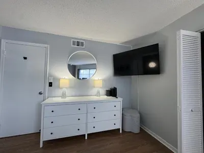 a bedroom with a white dresser and a mirror at Disney and Airport 15 minutes from Luxury Condo in Orlando