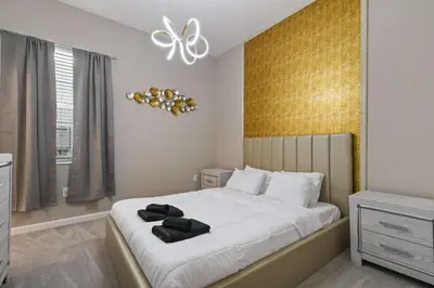 a bedroom with a large bed with a gold wall at Family-Friendly Luxury Home Near Disney & More in Kissimmee