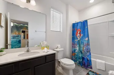 a bathroom with a sink and a toilet and a shower curtain at Spacious 12BR Disney Themed Home Pool/SPA/BBQ/Game in Kissimmee