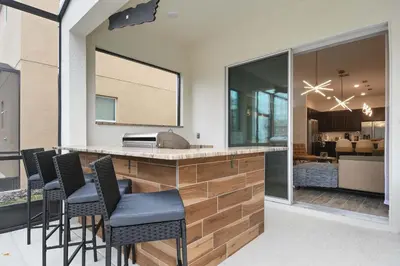 a kitchen with a bar with chairs and a living room at Spacious 12BR Disney Themed Home Pool/SPA/BBQ/Game in Kissimmee