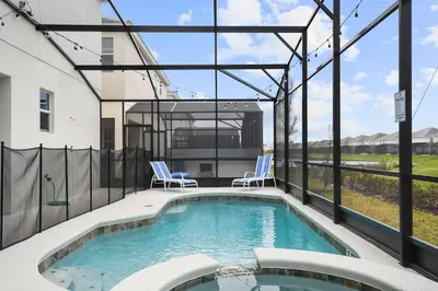 a swimming pool with two chairs and a building at Spacious 12BR Disney Themed Home Pool/SPA/BBQ/Game in Kissimmee
