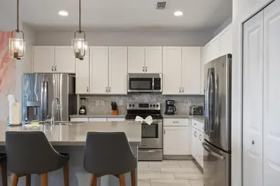 a kitchen with white cabinets and stainless steel appliances at Elegant Home with Pool & Spa, Close to Disney in Kissimmee