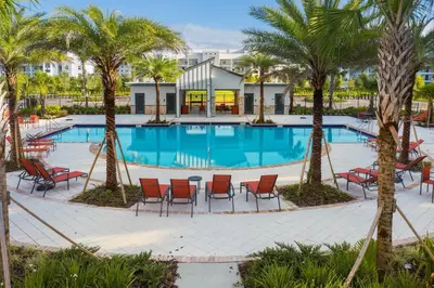 a swimming pool with palm trees and chairs at Storey Lake 2BR Cozy Resort Home Close to Disney in Kissimmee