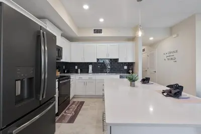 a kitchen with white cabinets and a black refrigerator at Storey Lake 2BR Cozy Resort Home Close to Disney in Kissimmee