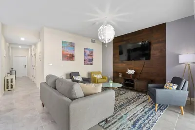 a living room with a couch and a tv on a wall at Storey Lake 2BR Cozy Resort Home Close to Disney in Kissimmee